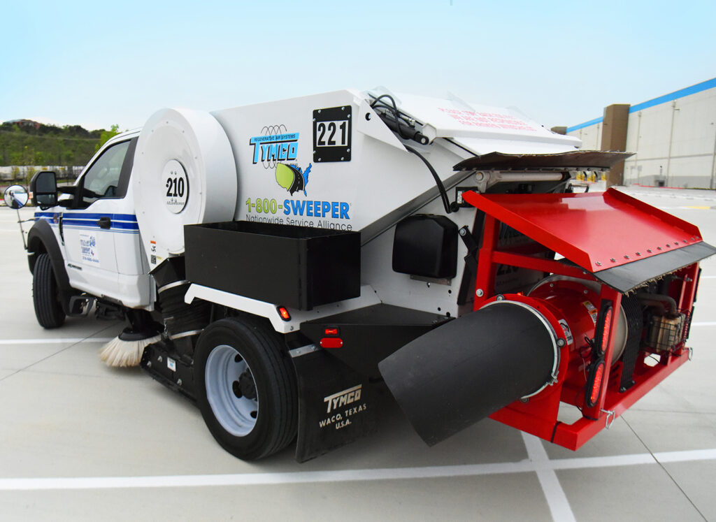 White street sweeper with red vacuum